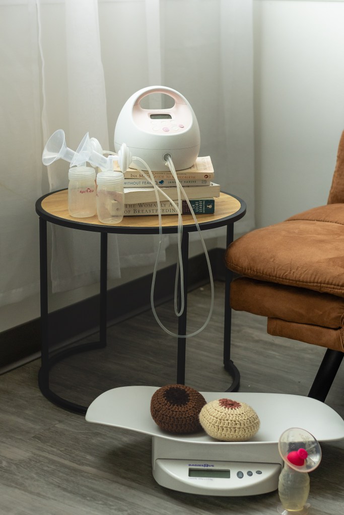 Breast models and a breast pump displayed on a table in a cozy, welcoming home setting for lactation education.